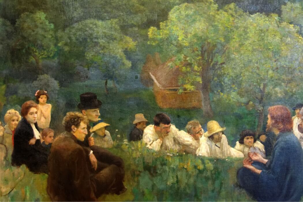 A group of men, women, and children gathered in a lush green forest clearing on a sunny day, listening attentively to a bearded man in a blue coat reading from a book while seated; some wear hats including top hats and straw hats, a horse-drawn cart and wooden boat appear in the background amid trees bathed in golden sunlight